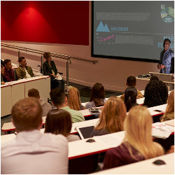 Students listen  to an instructor in a college lecture hall