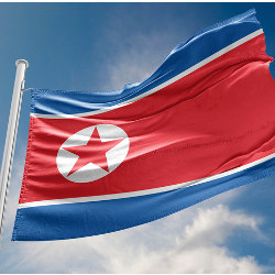 the North Korea flag waves against a blue sky