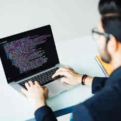 A young man typing on a laptop.