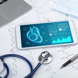 Smartphone on a doctor's desk shows visualizations of patient data.