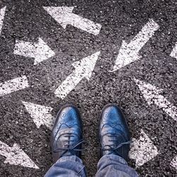 A pair of feet faces directional arrows on the ground, representing choices.