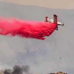 An airplane drops fire-extinguishing chemicals on a wildfire.