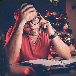 stressed worker on phone with Christmas tree in background