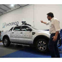 Paul Newman, founder of British autonomous vehicle software startup Oxbotica, next to a converted pickup truck that has been used to test self-driving operations with a mining company, in Oxford, U.K.