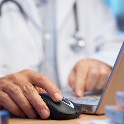 physician's hand on computer mouse at laptop computer