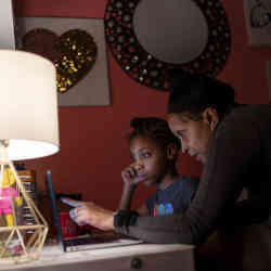 Abigail Schneider, 8, completes a level of her learning game with assistance from her mother April in her bedroom in Brooklyn, NY.