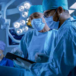 Surgeons consult a tablet computer during spinal surgery.