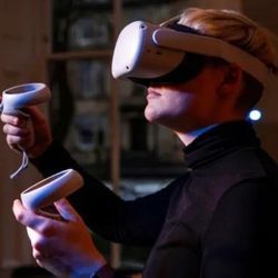 Person using a virtual reality headset and accompanying handheld hardware.