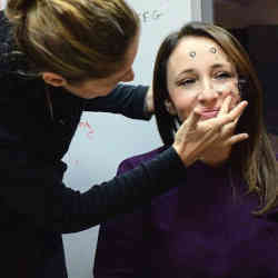 Yael Hanein of Tel Aviv University adjusts the electrodes on the face of a test subject.  