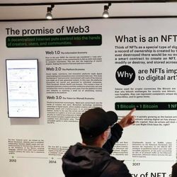 Attendees at a conference read posted information about Web3 and NFTs