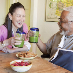 A senior shares a healthy beverage with a health aide. 