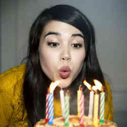 A young woman blows out the candles on a birthday cake.