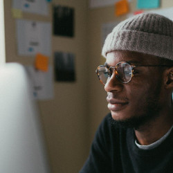 man in cap reading a computer screen