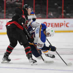 St. Louis Blues center Jordan Kyrou (25) falls over the stick of Ottawa Senators left wing Brady Tkachuk after a faceoff during the first period of an NHL hockey game two weeks ago in Ottawa, Ontario. 