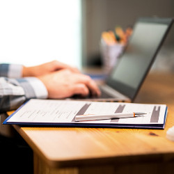 clipboard next to hands on laptop computer keyboard