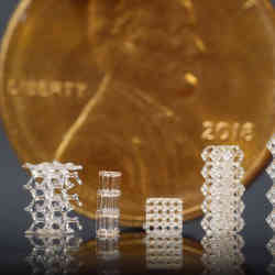 3D-printed glass lattices, displayed in front of a U.S. penny for scale.