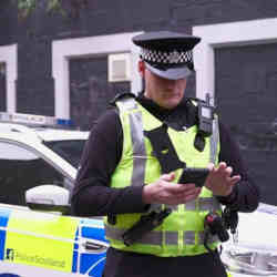 A policeman in Scotland access information on a digital device. 