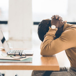 stressed worker with head down at laptop computer