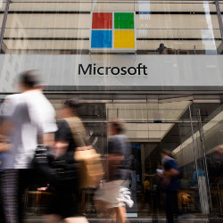 people walking past a building entrance with Microsoft name and logo