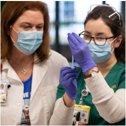 RN watches a nursing student prepare an injection