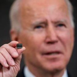 President Joseph Biden holds a microchip between two fingers.