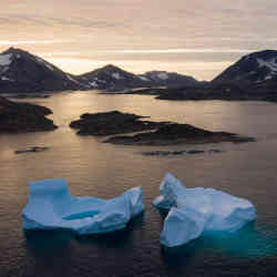 Icebergs float away as the sun rises near Kulusuk, Greenland.
