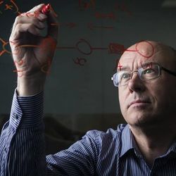 Chris Bishop, director of Microsofts AI4Science initiative, writing equations on a glass board..