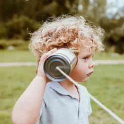 A young boy using a 'tin-can telephone'.