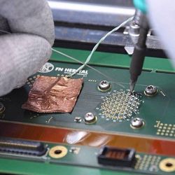 A technician solders a microchip to a PC board.