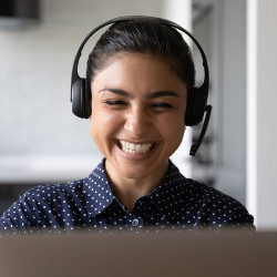 worker in earphones at a computer monitor laughing