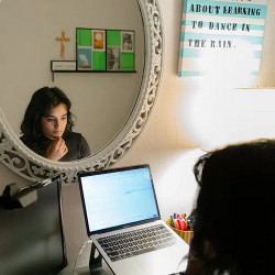 Rachel Castellino at a laptop computer in front of a mirror