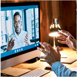 a worker on a video screen gestures to a coworker