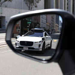 Spotting a self-driving Waymo in the rear-view mirror.