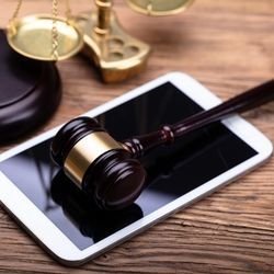A judge's gavel rests on a smartphone with scales of justice in background.