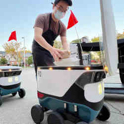 An Uber Eats employee loads the robots before they depart.