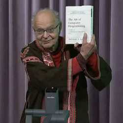 Donald Knuth holding up a volume of 'The Art of Programming'