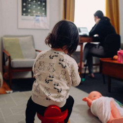 woman working from home while a child plays with toys