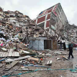 People stand in front of collapsed buildings following an earthquake in Kahramanmaras, Turkey.