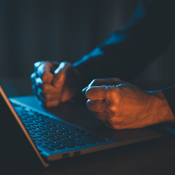 man's fists on a laptop computer