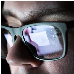 screen reflected in a man's glasses