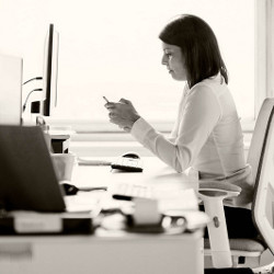 worker at a desk checks her phone