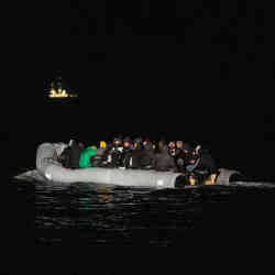 A lighted drone catching a late-night boatload of immigrants. 