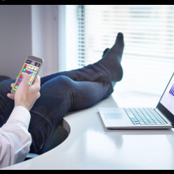 worker has his feet on a desk while playing games on a smartphone