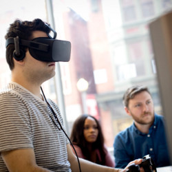 student wearing a virtual reality headset in front of a computer 