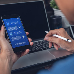 worker at laptop computer interacts with a chatbot via a mobile phone