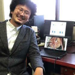 Hiroshima University assistant professor Yasufumi Yamada with an image of a greater horseshoe bat. 