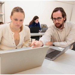 GWU senior Abbie McGrann works at a laptop computer with Assistant Professor Douglas Crawford 