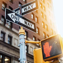 one-way and don't-walk signage on a city street corner