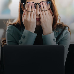 stressed worker rubbing her eyes with her hands