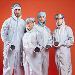 individuals in cleanroom attire holding semiconductor wafers